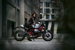 BMW R 12 nineT 2025 – Seitenansicht rechts mit Fahrerin, Aluminium-Silber