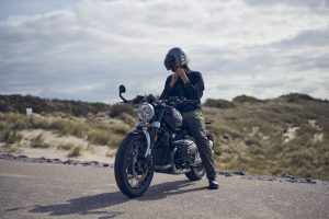 BMW R 12 nineT 2025 – schräge Frontansicht mit Fahrer am Strand, Schwarz