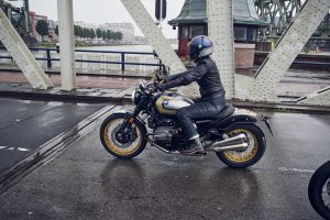 BMW R 12 nineT 2025 – Seitenansicht mit Fahrerin auf Brücke, Avus-Silber