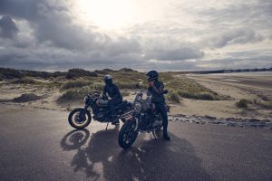 BMW R 12 und R 12 nineT 2025 – zwei Fahrer mit beiden Modellen am Strand, Schwarz
