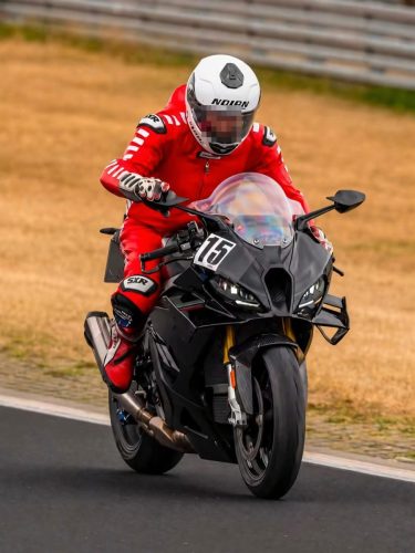 BMW S 1000 RR 2028 Erlkönig – Frontalansicht in Fahrt, Fahrer im roten Lederkombi, Winglets und goldene Gabelstandrohre erkennbar (Quelle: Instagram bt_moto_)