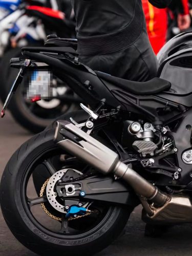 BMW S 1000 RR 2028 Erlkönig – Detailansicht am Heck mit unten angebrachtem blauem M-Bremssattel, Titan-Endschalldämpfer und goldener Kette (Quelle: Instagram bt_moto_)