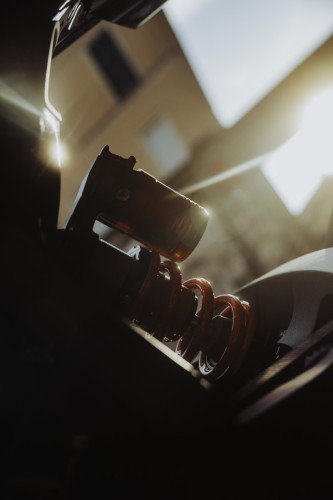 BRABUS URBAN E 2026 – Detailansicht des CNC-gefrästen Stoßdämpfers mit orangefarbener Feder im Gegenlicht