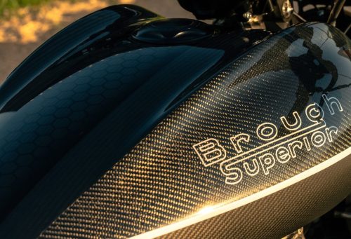 Brough Superior Dagger S 2026 – Tank-Detailansicht bei natürlichem Licht im Freien, Carbon-Oberfläche mit goldenem Schimmer und Waben-Struktur, Brough Superior Schriftzug in Gold, Tankdeckel