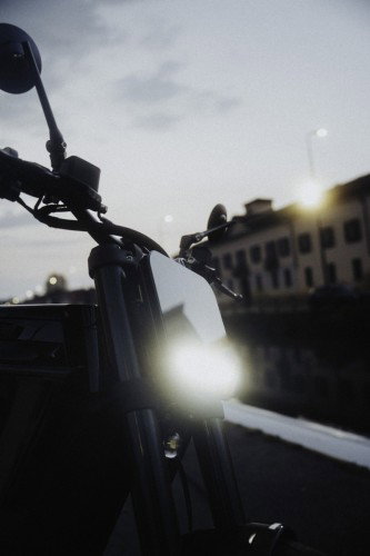 DAB 1a BRABUS 2026 – Frontdetail mit eingeschaltetem Scheinwerfer im Gegenlicht an einem Mailänder Kanal bei Sonnenuntergang