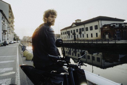 DAB 1a BRABUS 2026 – Fahrer in Lederjacke sitzend auf dem Motorrad am Naviglio-Kanal im Abendlicht