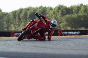 Ducati Desmo450 SM 2027 – Fahrer in Ducati Red mit Knie am Boden in der Kurve auf Asphalt