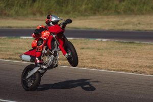 Ducati Desmo450 SM 2027 – Wheelie auf der Rennstrecke, Seitenansicht mit Motor und Auspuff