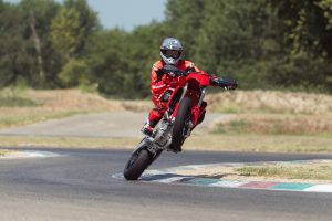 Ducati Desmo450 SM 2027 – Wheelie in der Kurve am Curb der Rennstrecke