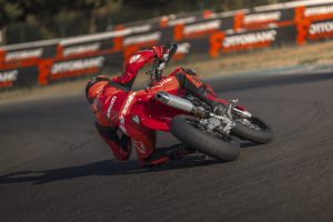 Ducati Desmo450 SM 2027 – Heckansicht in Schräglage mit Auspuff und Metzeler-Slicks