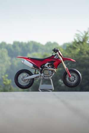Ducati Desmo450 SM 2027 – Seitenansicht rechts auf Montageständer vor Bäumen, Hochformat