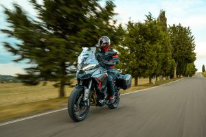 Ducati Multistrada V4 S Grand Tour 2027 – Fahraufnahme von vorn auf einer Allee mit Zypressen und Pinien, Fahrer in schwarz-roter Kombi