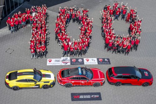 Ducati #WeRideAsOne 2026 – Luftaufnahme: Ducati-Mitarbeiter formen die Zahl 100 vor dem Werk in Borgo Panigale mit drei Audi-Fahrzeugen