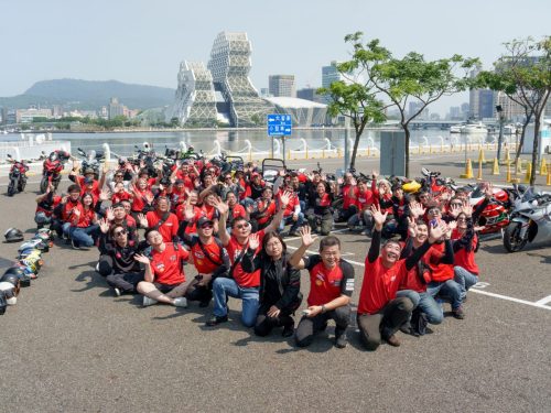 Ducati #WeRideAsOne 2026 – Gruppenfoto in roten Ducati-Shirts am Hafen von Kaohsiung, Taiwan, vor moderner Architektur