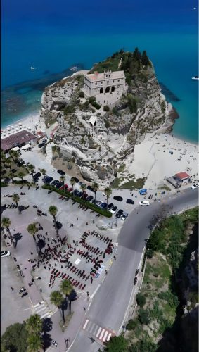 Ducati #WeRideAsOne 2026 – Luftaufnahme: Ducati-Motorräder am Fuß des Felsens von Tropea mit dem Kloster Santa Maria dell'Isola in Kalabrien, Italien