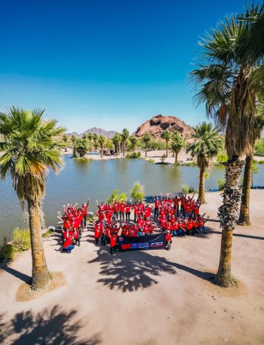 Ducati #WeRideAsOne 2026 – Gruppenfoto in roten T-Shirts in Wüstenlandschaft bei Phoenix, Arizona, USA, mit Palmen und See