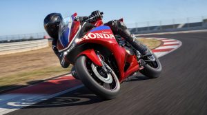 Honda CBR500R FOUR 2027 in Ignition Red Tricolour in Schräglage auf der Rennstrecke über den Curb
