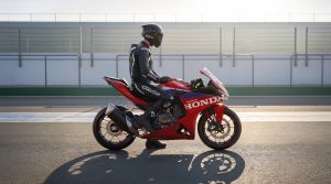 Fahrer auf der stehenden Honda CBR500R FOUR 2027 in Ignition Red Tricolour in der Boxengasse im Gegenlicht