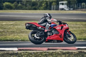 Honda CBR600RR 2027 in Ignition Red HRC TriColour in Schräglage auf der Rennstrecke, Seitenansicht von rechts