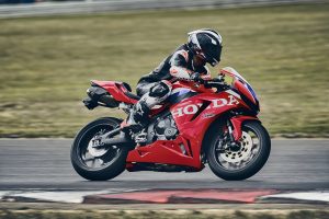 Honda CBR600RR 2027 in Ignition Red HRC TriColour in Schräglage nach links vor Grünstreifen