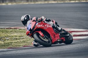 Honda CBR600RR 2027 in Ignition Red HRC TriColour in tiefer Schräglage über den Curb
