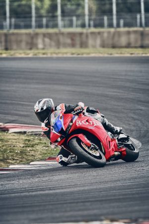 Honda CBR600RR 2027 in Ignition Red HRC TriColour in Rechtskurve auf der Rennstrecke, Hochformat