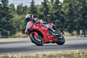 Honda CBR600RR 2027 in Ignition Red HRC TriColour in Rechtskurve auf der Rennstrecke vor Waldkulisse