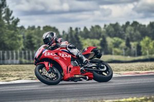 Honda CBR600RR 2027 in Ignition Red HRC TriColour in Linkskurve vor bewölktem Himmel