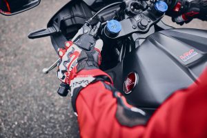Honda CBR600RR 2027 – Fahrerhand am linken Lenkerschalter, Gabeleinsteller und HRC-Logo auf dem Tank