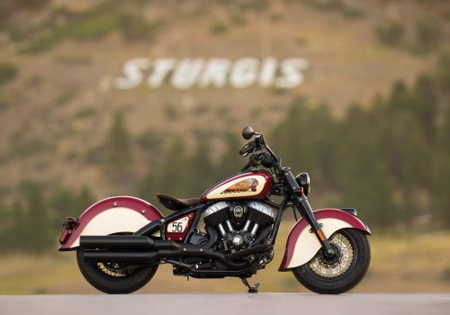 Rechte Seitenansicht in Indian Motorcycle Red und Cream vor dem weißen STURGIS-Schriftzug am Berghang in South Dakota