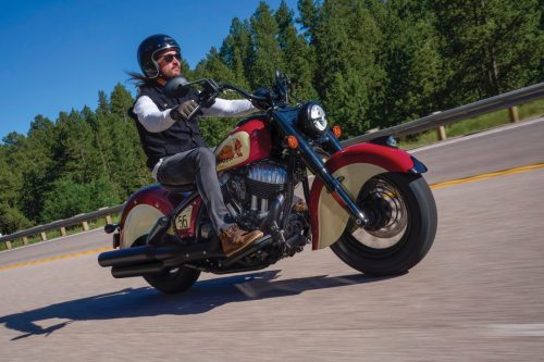 Fahraufnahme von vorn auf einer von Nadelwald gesäumten Straße in den Black Hills, Fahrer mit offenem Jethelm