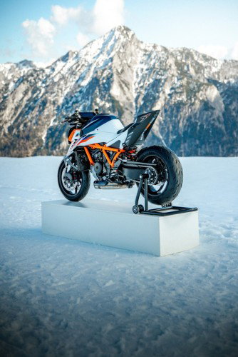 KTM 1390 Super Duke RR 2026 – Heck-Dreiviertelansicht auf Podest im Schnee vor markantem Berggipfel