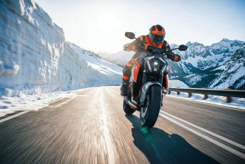 KTM 1390 Super Duke RR 2026 – Action-Aufnahme: Fahrer beschleunigt auf Passstraße durch Schneekorridor im Hochgebirge
