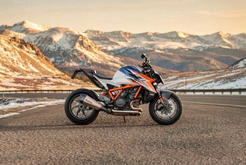 KTM 1390 Super Duke RR 2026 – Seitenansicht rechts auf Passstraße vor verschneiter Alpenkulisse im Abendlicht
