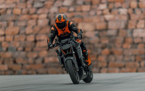 KTM 1390 Super Duke RR Track 2026 – Kurvenfahrt mit Fahrer in orange-schwarzer KTM-Lederkombi und voller Schräglage