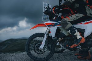 KTM 690 Rally 2027 – Detail von Vorderrad, WP-Gabel und Fronttank mit aufsitzendem Fahrer in Enduro-Stiefeln