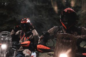 KTM 690 Rally 2027 – zwei Fahrer bei Regen im dunklen Wald, orange Handprotektoren und eingeschalteter Scheinwerfer