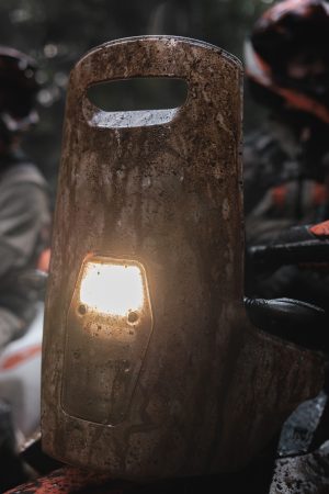 KTM 690 Rally 2027 – Nahaufnahme des komplett schlammverkrusteten Rally-Towers mit durchscheinendem Scheinwerfer