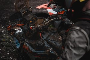 KTM 690 Rally 2027 – Blick von oben auf das verschlammte Cockpit mit beiden Fronttank-Deckeln und Lenkerschaltern