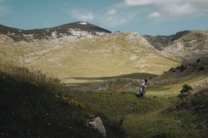 KTM 690 Rally 2027 – einzelner Fahrer auf grasbewachsener Hochebene vor Kalksteingebirge bei blauem Himmel