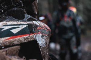KTM 690 Rally 2027 – schlammverkrustete Tankverkleidung mit Rally-Dekor, dahinter zwei Fahrer in Enduro-Kluft