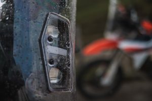 KTM 690 Rally 2027 – Nahaufnahme der LED-Scheinwerfereinheit hinter dem regennassen Windschild des Rally-Towers