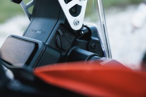 KTM 690 Rally 2027 – Detail am Rally-Tower mit 12-V-Bordsteckdose unter Gummikappe neben dem TFT-Display