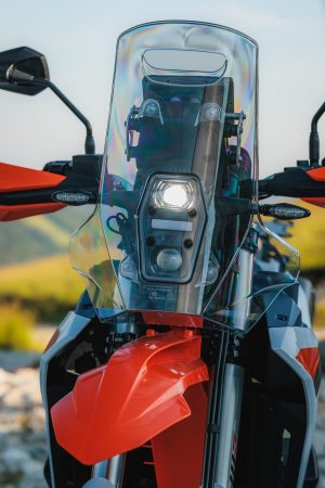 KTM 690 Rally 2027 – Front mit eingeschaltetem LED-Scheinwerfer, hohem Windschild, Handprotektoren und Upside-down-Gabel