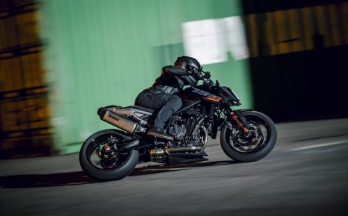 KTM 790 Duke 2027 in Action – Mitzieher des fahrenden Motorrads vor grüner Containerwand