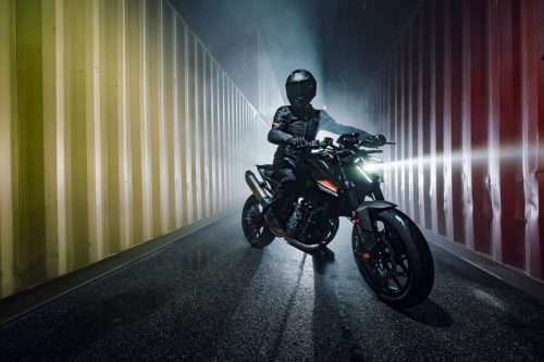 KTM 790 Duke 2027 – Fahrer mit eingeschaltetem Scheinwerfer in einer Container-Gasse