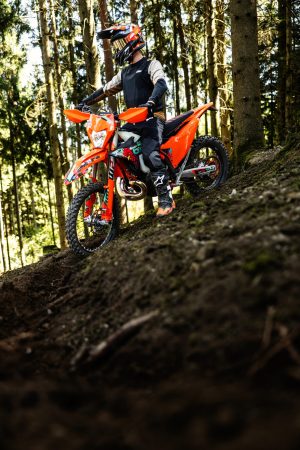 KTM 300 EXC 6DAYS 2027 – Enduro-Fahrer fährt einen steilen Erdhang im Wald hinauf