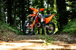 KTM 300 EXC 6DAYS 2027 – Seitenprofil auf einer Waldkuppe im 6DAYS-Portugal-Design
