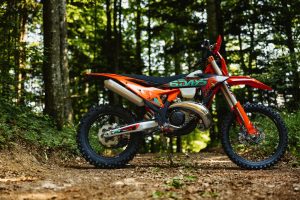 KTM 300 EXC 6DAYS 2027 – Seitenprofil auf einem Waldweg mit orange lackiertem Rahmen