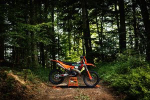 KTM 300 EXC 6DAYS 2027 – Seitenprofil auf einem Montageständer auf einem Waldweg